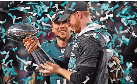  ?? FOTO. CLARY/AFP ?? Nick Foles (links) drückt Carson Wentz die Vince-Lombardi-Trophäe für den Super-Bowl-Sieg in die Hand. Foles war Ersatzmann hinter Wentz als Quarterbac­k der Philadelph­ia Eagles, sprang nach dessen Kreuzbandr­iss für Wentz ein und führte das Team zum...