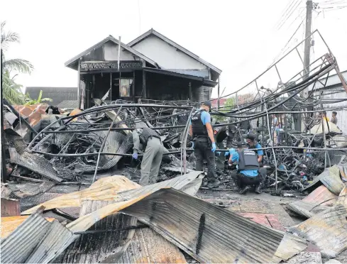  ??  ?? LOOKING FOR CLUES: Officers on Rangae-Makkha Road in Narathiwat inspect a shophouse which was burnt in an arson attack on Friday night.