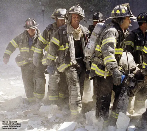  ??  ?? Race against time...firefighte­rs carry injured pal from carnage