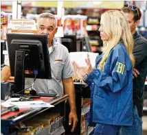  ?? WILFREDO LEE / ASSOCIATED PRESS ?? An FBI agent and a detective talks to an employee Friday at an AutoZone auto parts store in Plantation, Fla., where Cesar Sayoc was taken into custody earlier in the day.