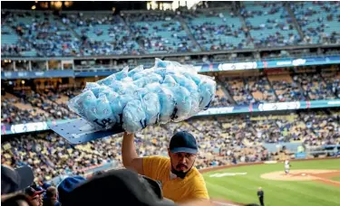  ??  ?? A food-seller offers candy floss to spectators while the New York Mets take on the Los Angeles Dodgers at Dodger Stadium.