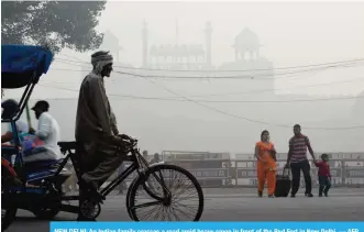  ??  ?? NEW DELHI: An Indian family crosses a road amid heavy smog in front of the Red Fort in New Delhi. — AFP