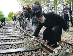  ?? PETER DEJONG / THE ASSOCIATED PRESS FILES ?? A rabbi puts a rose on tracks at former concentrat­ion camp Westerbork, rememberin­g more than 100,000 Jews who were transporte­d from there to Nazi death camps.