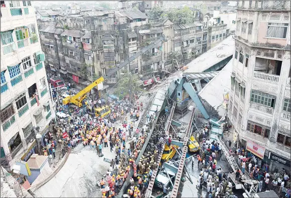  ??  ?? Indian rescue workers and volunteers try to free people trapped under the wreckage of a collapsed fly-over bridge in Kolkata on March 31. At least 21 people were killed and dozens more injured when a fly-overcollap­sed in the busy Indian city on March 31, an official said, as emergency workers battled to rescue people trapped under the rubble. (AFP)