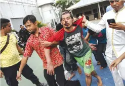  ??  ?? RIAU PROVINCE: Plain-clothed police officers escort recaptured inmates following their escape at Sialang Bungkuk Prison in Pekanbaru, Riau province, Indonesia yesterday. — AP