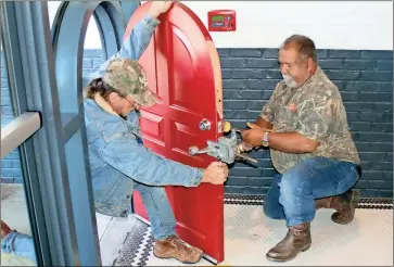  ??  ?? Darrell Ballard (left) and Thomas Spence install the ‘little red door” at the entrance to the new Truett’s Chick-fil-A. / Doug Walker