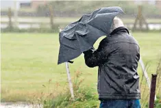  ??  ?? At the mercy of the elements: an umbrella proves futile against Welsh rain in Porthcawl