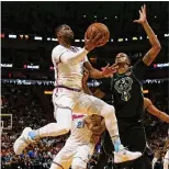  ?? DAVID SANTIAGO / EL NUEVO HERALD ?? Dwyane Wade (left) shoots against the Milwaukee Bucks’ John Henson during his first game back with the team.