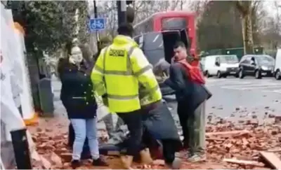  ??  ?? Shock: Passers-by give the woman first aid amid the scattered broken bricks and wood