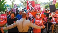  ??  ?? 一群民眾在東洛杉磯縣­警局外舉牌高呼口號支­持SB54提案，也就是所謂的「庇護州」提案。（洛杉磯時報）