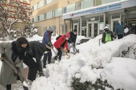  ?? Pablo Blazquez Dominguez / Getty Images ?? Neighbors volunteer to help clear snow around a Madrid hospital. Storm Filomena brought more than 20 inches of snow to the Spanish capital.