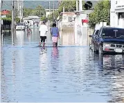  ??  ?? A couple negotiates their way through flood waters along Tharpe Street in Falmouth in 2005.