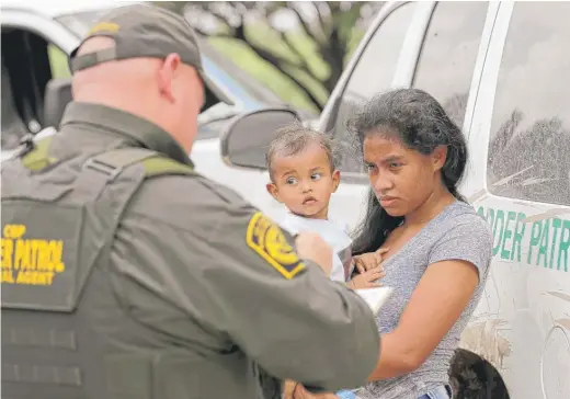  ?? DAVID J. PHILLIP/ AP ?? Amother migrating from Honduras holds her 1- year- old child while surrenderi­ng to U. S. Border Patrol agents after illegally crossing the border June 25.