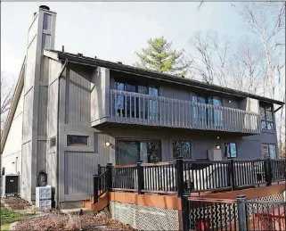  ??  ?? The main bedroom and the smaller upstairs bedroom have access to a balcony deck off the back of this cedar-sided home. The 2-level composite deck leads down to the wooded backyard, part of which is fenced.