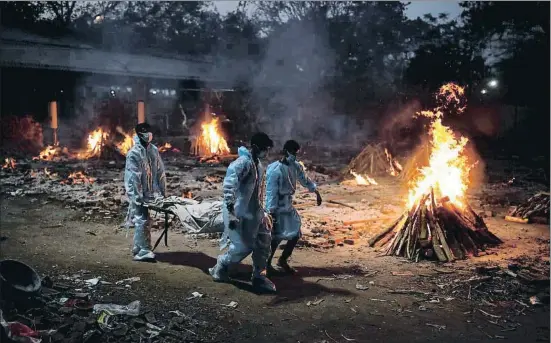  ?? ADNAN ABIDI / REUTERS ?? Tres personas llevando el cadáver de un fallecido por covid a incinerar, ayer en Nueva Delhi