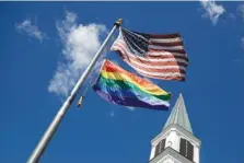  ?? AP PHOTO/CHARLIE RIEDEL ?? A rainbow gay pride flag flies along with the U.S. flag in front of the Asbury United Methodist Church in Prairie Village, Kan., on Friday.