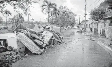  ?? Jose A. Iglesias photos / El Nuevo Herald / TNS ?? Debris left from Hurricane Maria, as well as furniture, appliances and ruined vehicles, litter a street in Toa Baja, Puerto Rico, three weeks after the storm battered the island.