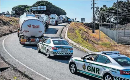  ?? / PATRICIA DE MELO (AFP) ?? Coches de la policía escoltan camiones cisterna, ayer en Aveiras de Cima (Portugal).
