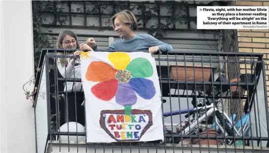  ?? Alessandra Tarantino ?? > Flavia, eight, with her mother Silvia as they place a banner reading ‘Everything will be alright’ on the balcony of their apartment in Rome