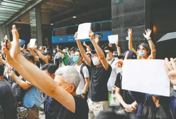  ?? TYRONE SIU / REUTERS ?? Supporters of an arrested protester raise blank sheets of white paper outside of a Hong Kong
court on Friday to avoid using slogans now banned under the new national security law.