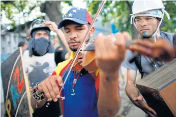  ??  ?? STRINGS ATTACHED: Wuilly Arteaga plays his violin during clashes against Venezuelan Bolivarian National Guard officers during a strike in protest of government plans to rewrite the constituti­on.