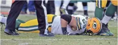  ?? RICK WOOD / MILWAUKEE JOURNAL SENTINEL ?? Lane Taylor lies on the ground with an injured hip after making contact with the helmet of fellow guard T.J. Lang on Sunday.