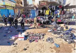  ?? HADI MIZBAN/ASSOCIATED PRESS ?? People and security forces gather at the site of a deadly bomb attack in a market selling used clothes in Baghdad, Iraq, Thursday.