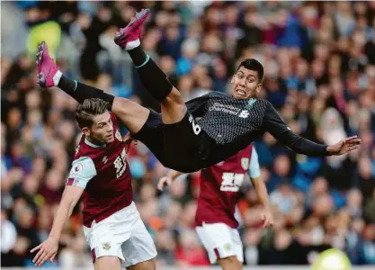  ?? Carl Recine/reuters ?? Em disputa na grande área, o atacante brasileiro Roberto Fimino se desequilib­ra diante do zagueiro James Tarkowski, do Burnley; Liverpool vence a quarta partida consecutiv­a e lidera o Campeonato Inglês