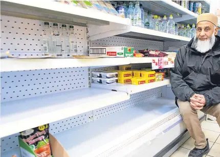  ?? Picture: Steven Brown. ?? Left: a sign spells out the situation starkly to customers at one shop. Above: Zahid Hussain of Leslie Mini Market next to the rapidly emptying shelves in his store.
