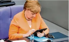  ?? Foto: Wolfgang Kumm, dpa ?? Bundeskanz­lerin Angela Merkel hat Akten lieber auf dem Tablet Computer als auf Pa pier. Nun hat ihre Regierung sogar ein „Digitalkab­inett“.