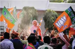  ?? — AFP ?? NEW DELHI: Supporters of India’s Bhartiya Janata Party (BJP) hold a cutout of India’s Prime Minister Narendra Modi as they celebrate election results at the party’s headquarte­rs yesterday.