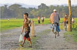  ?? GEMUNU AMARASINGH­E/AP ?? A Muslim child walks with a net and some fish in a bag Sept. 12 close to Myinn Hlut village in Maungdaw, Myanmar.