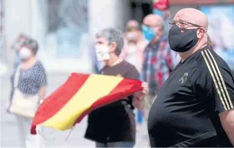  ?? REUTERS ?? People wearing protective face masks stand during a daily minute of silence to commemorat­e victims of Covid-19 in Madrid.