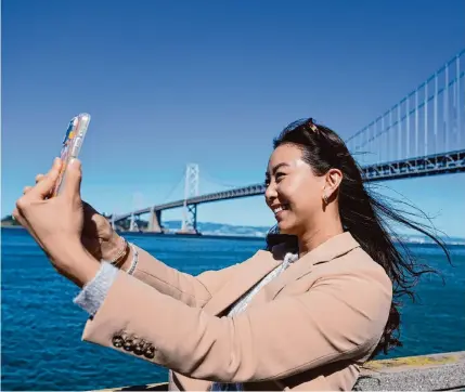  ?? Eric Risberg/associated Press ?? Content creator Cynthia Huang Wang works near the San Francisco-oakland Bay Bridge this month. Wang tried her hand at full-time online content creation after she was laid off from her brand marketing job in February 2023.