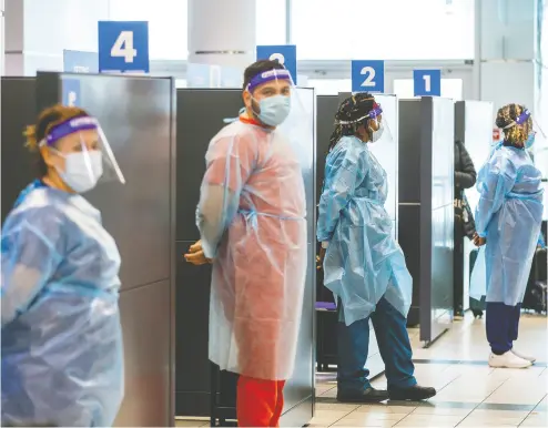  ?? CARLOS OSORIO / reuters FILES ?? Health-care workers prepare to test passengers at Toronto’s Pearson airport last week.