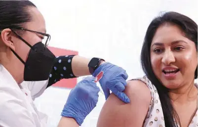  ?? ANTONIO PEREZ/CHICAGO TRIBUNE ?? Pharmacy manager Lilliann Kong gives Priyanka Reddy a vaccine at a CVS in Chicago in November. In Florida, fewer than 1 in 13 people aged 18 to 64 have received the bivalent booster. Only Alabama, Louisiana and Mississipp­i have lower rates.