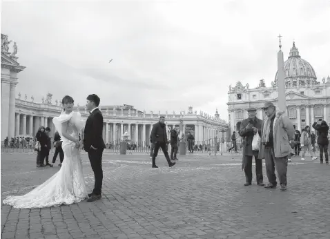  ?? Alessandra Tarantino/Associated Press ?? ■ People watch as a couple in wedding clothes pose for photos Jan. 17 in front of St. Peter’s Square at the Vatican.