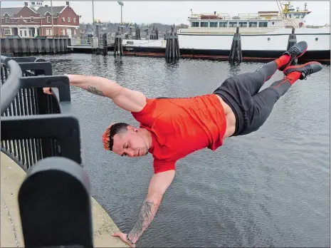  ?? SARAH GORDON/THE DAY ?? Samer Delgado, a personal trainer and calistheni­cs enthusiast, holds a human flag pose while training on April 12, at Waterfront Park in New London. The New London resident will compete in “American Ninja Warrior” in May.