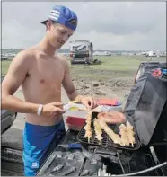  ?? DON Healy/leader-post ?? Brandon Ewanchuk from Saskatoon cooks sausage and chicken souvlaki on his truck while waiting in the lineup to
leave the Craven Country Jamboree on Monday.