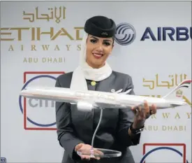  ?? PICTURE: REUTERS ?? ON THE MOVE: A flight attendant of Etihad Airways holds a model of the Airbus A350 during the Dubai Airshow. The airlines said it had bought a 33.3 percent stake in Swiss carrier Darwin Airline, adding to the company’s portfolio of minority stakes in...