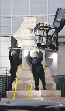 ?? Gerald Herbert Associated Press ?? WORKERS wearing masks and f lak jackets dismantle the Liberty Monument in New Orleans overnight this month.