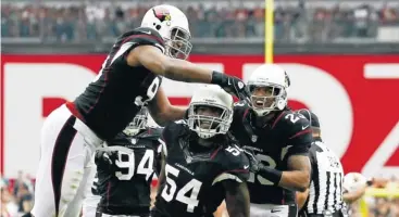  ?? ROB SCHUMACHER, THE (PHOENIX) ARIZONA REPUBLIC ?? Quentin Groves, center, and the Cardinals defense celebrate a sack of the Eagles’ Michael Vick.