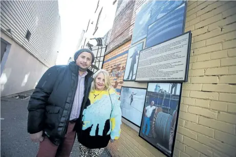  ?? JULIE JOCSAK/POSTMEDIA NETWORK ?? Julio Batres, Downtown BIA chairman and Constance Cochrane, former sister-in-law of wirewalker Jay Cochrane, are photograph­ed by a new memorial in Daredevil Alley for the wirewalker, who died of cancer in 2013.