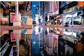  ?? FOTO: CRAIG RUTTLE/AP ?? Die Lichter am Times Square werden in Wasserlach­en reflektier­t, die sich während der Regenfälle auf der Straße gebildet haben.