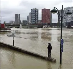  ?? STÉPHANE DELFOUR/AFP ?? A man fishes off a barrier partially submerged by the water of the swollen Seine river in Paris yesterday.