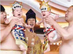  ??  ?? ... Sumo wresters hold up crying babies in front of a referee (centre) clad in a traditiona­l costume during a ‘Baby-cry Sumo’ event at the Kamegaike-Hachiman Shrine in the Japanese city of Sagamihara on Sunday. Some 150 babies aged under two took part...