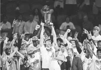  ?? IMAGES MARK RALSTON/AFP/GETTY ?? Dirk Nowitzki, center, and the Dallas Mavericks celebrates with teammates after winning the NBA Finals against the heavily favored Heat.