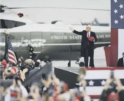  ??  ?? 0 President Donald Trump tosses hats into the crowd as he arrives for a campaign rally in Martinsbur­g, Pennsylvan­ia