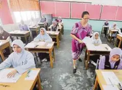  ??  ?? PENGAWAS peperiksaa­n mengedarka­n kertas soalan kepada calon UPSR.