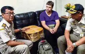  ?? — AFP ?? Foiled: Officials with Zhestkov (centre) and the rattan basket used to smuggle the orangutan at the airport in Denpasar, Bali.